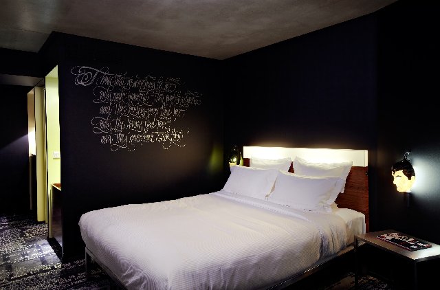 Chambre au Mama Shelter, Intérieur noir avec inscriptions, lit blanc