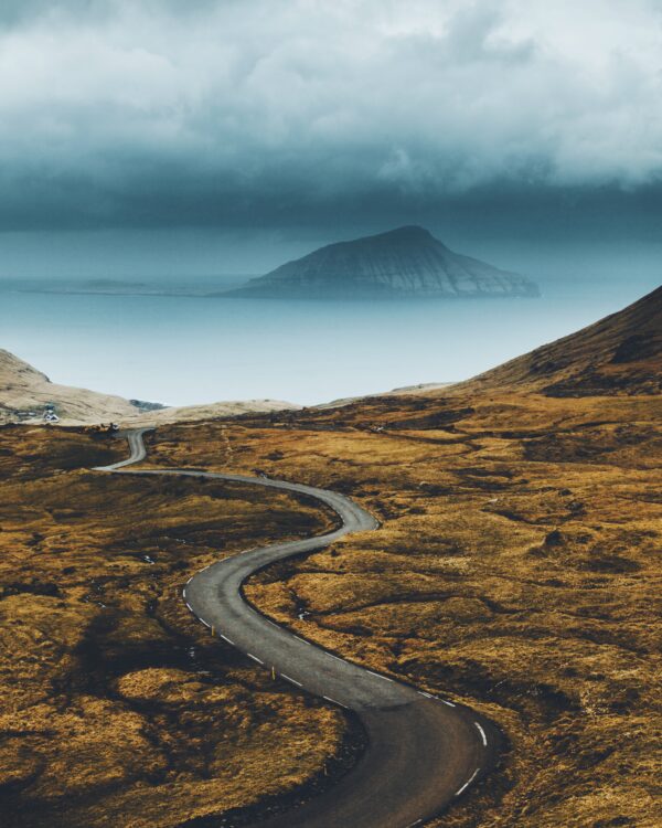 Une route qui serpente vers des falaises et la mer, dans les landes sauvages des îles Féroé
