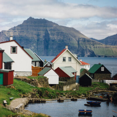 Maisons blanches avec toits orange au bord de la mer et entourées de falaises, îles Féroé, Danemark