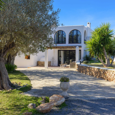 Une maison blanche avec des arcades vitrées dans un paysage d'oliviers à Ibiza