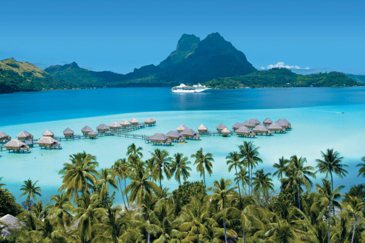 Vue d'un lagon turquoise et de villas sur pilotis à Bora Bora, qui fait partie des plus belles croisières du Ponant 