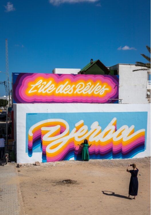 Ile de Djerba en Tunisie: deux femmes qui se prennent en photo devant un graff multicolore "Djerba"