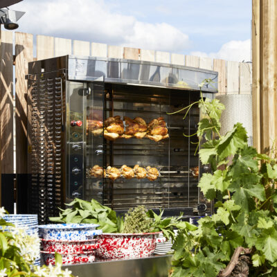 Une rôtissoire avec des poulets en train de griller sur le rooftop du Mamma Shelter Paris-East