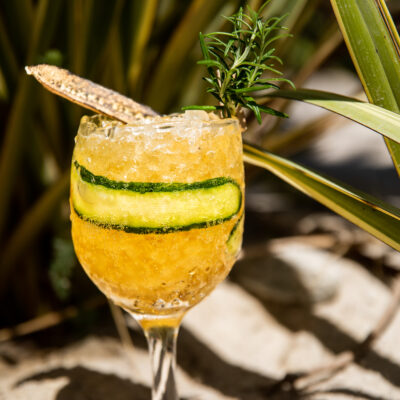 Un coktail signature orangé et glacé posé sur le sable de la plage privée de Nikki Beach, à St Tropez