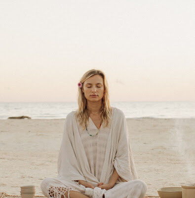 Jeune femme méditant sur la plage, dans la position du lotus, sur l'île grecque de Kea, dans les Cyclades