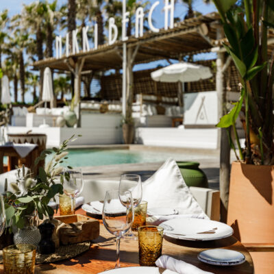 Une table dressée sous un pin parasol, sur la plage privée de Nikki Beach, à St Tropez