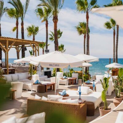 Des canapés et parasols blancs sur une terrasse du Nikki Beach Marbella, l'un des meilleurs clubs de plage de Méditerranée