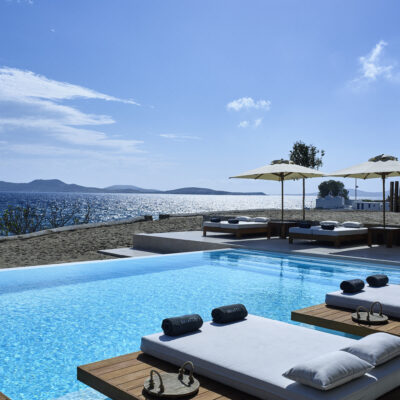 Une piscine entourée de transats et de sunbeds, au bord de la mer Egée, à l'hôtel Bill & Coo où se trouve l'une des plus belles piscines de Mykonos