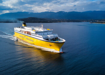 Un navire à la coque jaune de la Corsica Ferries naviguant le long des côtes de Méditerranée