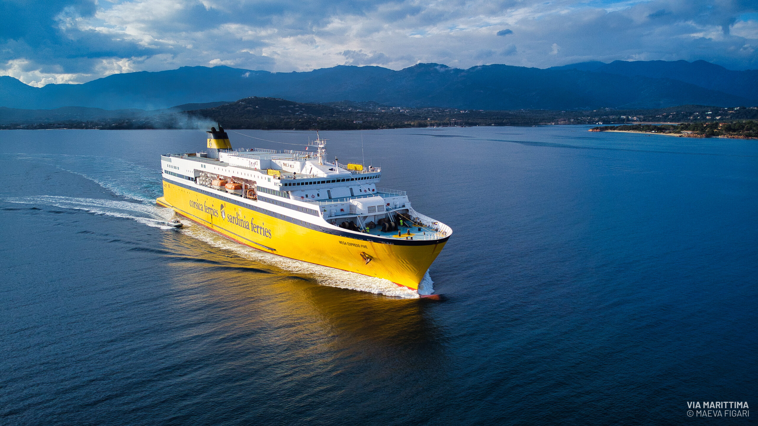 Un navire à la coque jaune de la Corsica Ferries naviguant le long des côtes de Méditerranée
