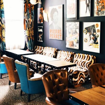 Une salle de restaurant de La Guitoune, adresse réputée du bassin d'Arcachon, avec des murs bleus décorés de toiles contemporaines, des tables et des canapés en cuir façon chesterfield