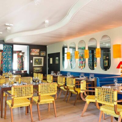 Une salle du restaurant de La Guitoune, adresse réputée du bassin d'Arcachon, avec de nombreux miroirs au mur, des appliques jaunes, des chaises tressées