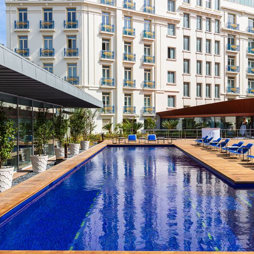 Une vue de la longue piscine en L d'un beau bleu profond qui se trouve à l'arrière de l'Hôtel Martinez à Cannes