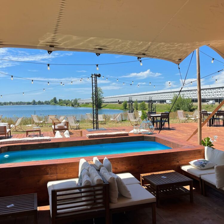 La terrasse des Planches Ephémères, une guinguette au bord du lac de Bordeaux, avec des canapés blancs qui entourent un bassin rectangulaire