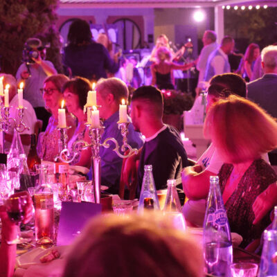 Une longue table dressée avec de grands chandeliers qui éclairent les nombreux convives de la soirée Bohemia organisée par l'hôtel L'Imperator lors de la Feria des Vendanges de Nîmes