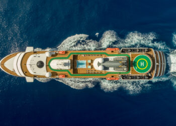 Vue aérienne et du dessus du navire de croisière musicale le World Explorer, avec sa piste d'atterrissage pour hélico, sa piscine et ses ponts en bois