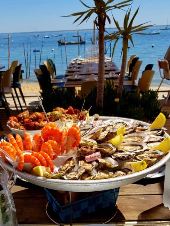 Un plateau de crevettes et d'huîtres posé sur une table, sur la terrasse d'une cabane à huîtres du village de l'Herbe, dans le bassin d'Arcachon