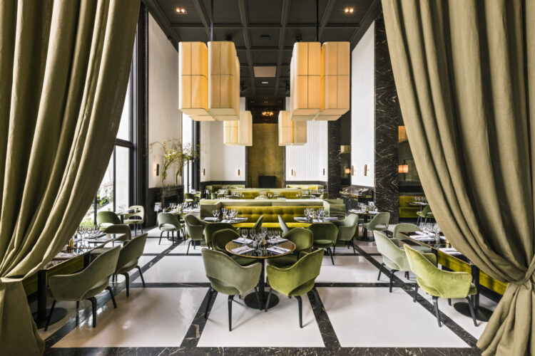 Hauts plafonds, murs gris, fauteuils de velours vert et hautes fenêtre du restaurant Monsieur Bleu, l'une des adresses à tester pendant le fashion week de Paris