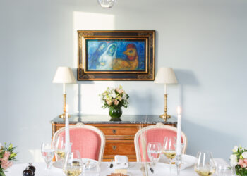 L'élégante salle à manger de la Suite Paris de l'Hôtel Le Bristol Paris, avec une superbe table dressée pour un dîner raffiné, face à une toile de Marc Chagall