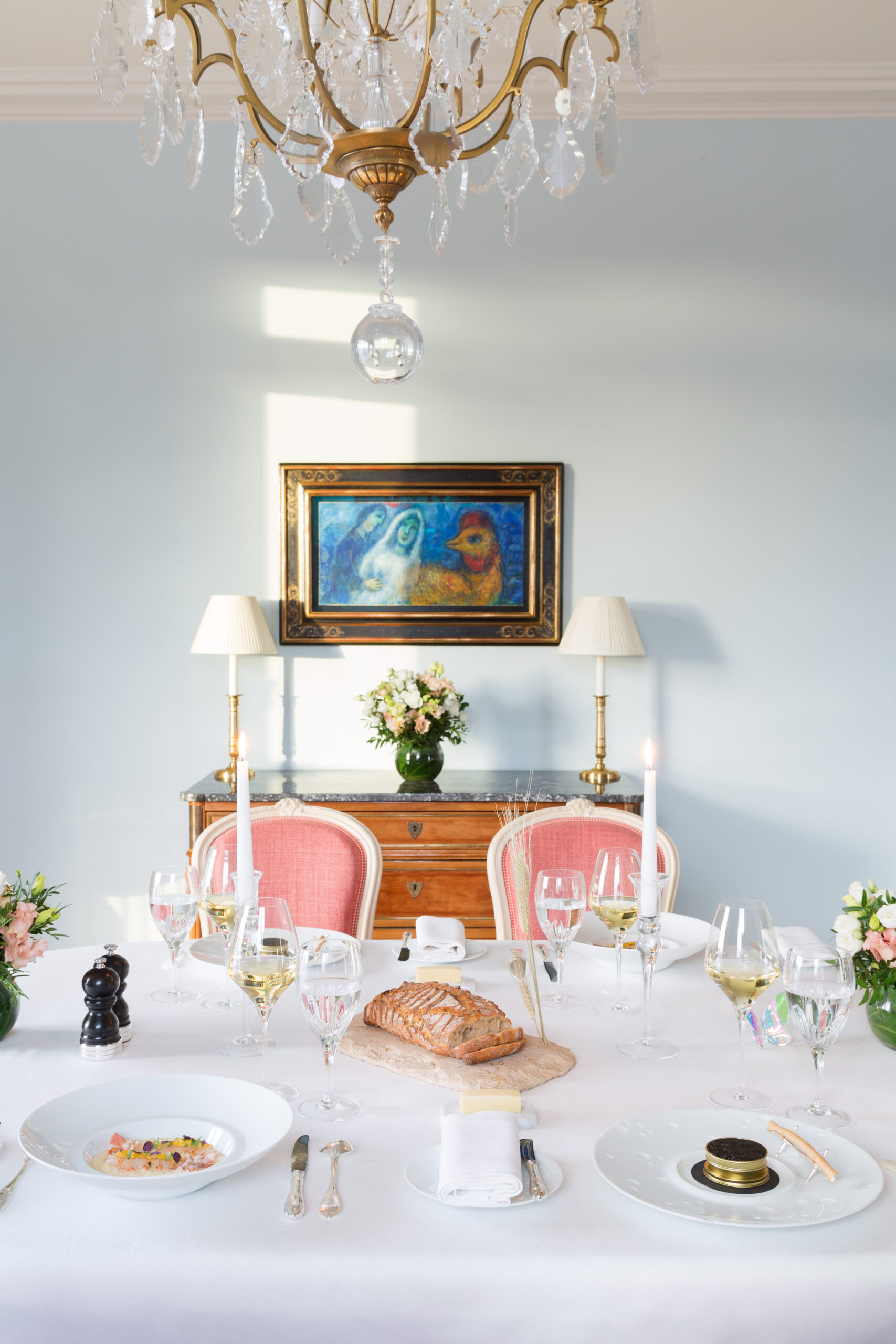 L'élégante salle à manger de la Suite Paris de l'Hôtel Le Bristol Paris, avec une superbe table dressée pour un dîner raffiné, face à une toile de Marc Chagall