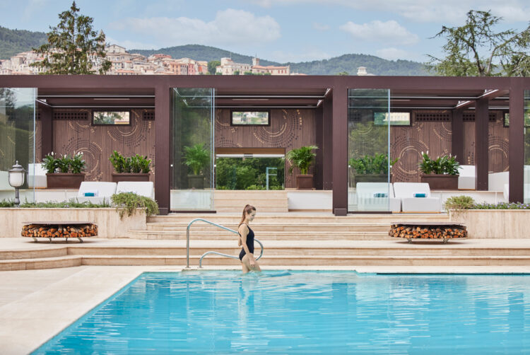 Les Thermes Romains du Palazzo Fiuggi en Italie, avec une grande piscine, des braseros et de confortables chaises longues étendues face à la vue sur les montagnes boisées