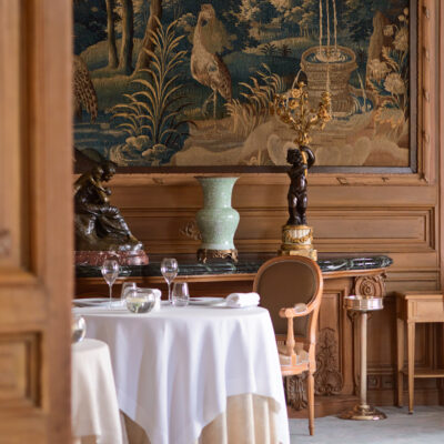 Une table juponnée dressée pour le diner sous une tapisserie de chasse du Relais & Château Domaine Les Crayères