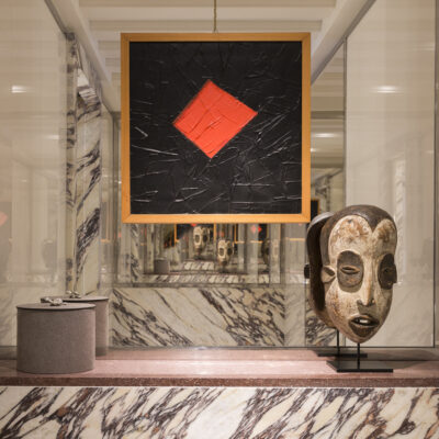 Vue d'une salle de bain en marbre noir et blanc de l'une des chambres de l'hôtel Portrait Milano, avec une toile moderne et un masque africain