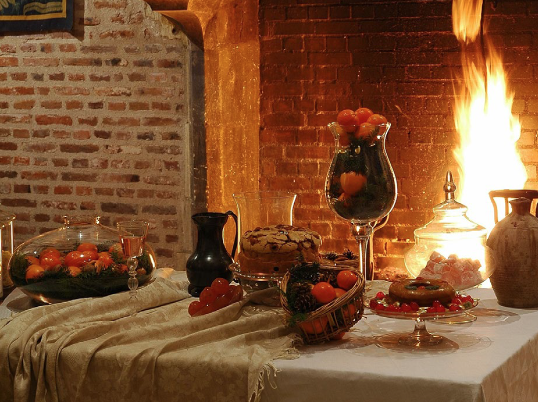 Une table chargée de coupes et de paniers de fruits et légumes d'automne, dressée devant un feu de cheminée au Clos Lucé
