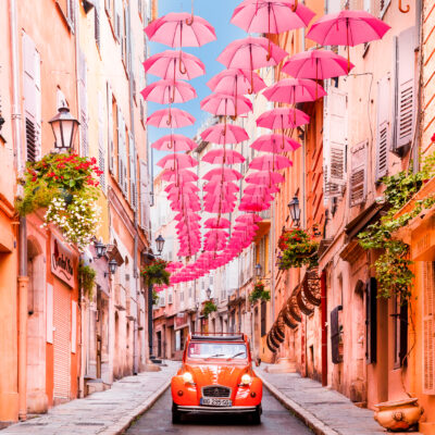 Une 2 CV orange dans une rue couverte de parapluies oranges, photo de Loïc Lagarde